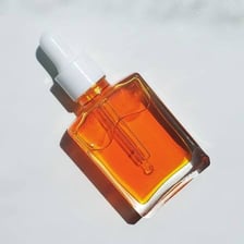 A glass facial serum bottle with a dropper beside skin-care products