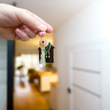 A renter holding keys outside an apartment