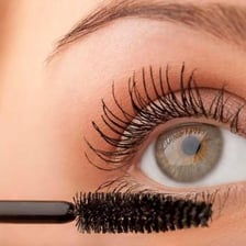 A mascara wand being applied to a person’s eyelashes