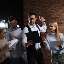 An actor rehearsing dialogue from a script on a stage.