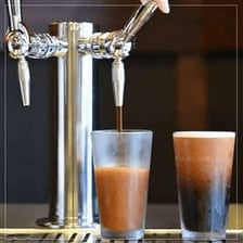 Nitro cold brew coffee being poured with a foamy head