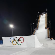 A snowboarder performing a trick above a large Big Air ramp