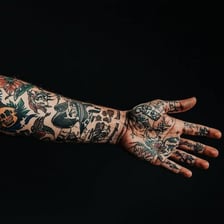 Tattoo ink beside a person’s tattooed arm