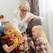 A smiling grandparent showing affection to young grandchildren.