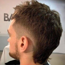 A side-profile view of a haircut that is short in front and longer in back.