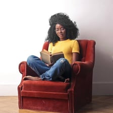 A person reads a book while sitting in an armchair.