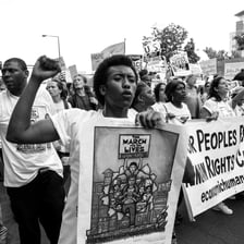 A person standing defiantly during a protest