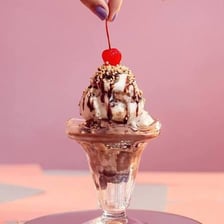 An ice-cream sundae topped with whipped cream and a cherry