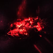 A glowing ember among the remaining coals of a campfire.