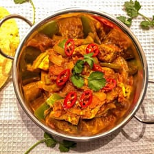 A bowl of curry garnished with chili peppers