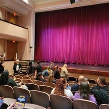 A theater stage and paintings displayed in a gallery.