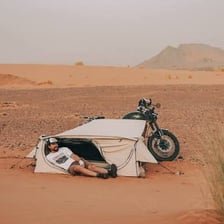 A traveler and tent in a desert landscape.