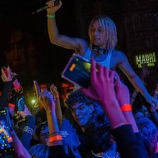 A rapper performing onstage under moody concert lighting.