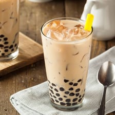 A cup of bubble tea contains dark tapioca pearls.