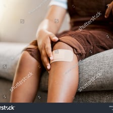 A child holding a lightly bandaged finger after a minor injury.