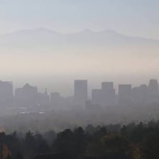 A city skyline partially obscured by a thick layer of smoggy haze.