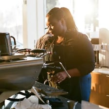 A barista preparing coffee behind a café counter