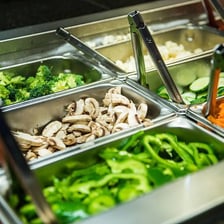 A salad bar with bowls of salad toppings and bottled dressings