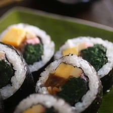 A sliced futomaki roll with a dark nori seaweed wrapper.