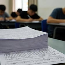 A student completing a paper examination in a classroom