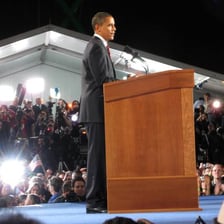 A speaker delivering a celebratory victory speech from a podium.