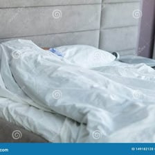 A person asleep underneath bed covers.