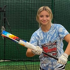 A softball batter holding the bat to tap the ball softly.