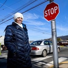 A person looking toward a sign on a street.