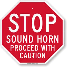 A car on a road using its horn to alert nearby traffic.
