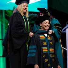 A graduate student wearing doctoral regalia at a graduation ceremony