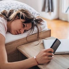 A tired person resting with eyes closed near a bed