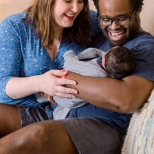 A parent holding a newborn baby at home.
