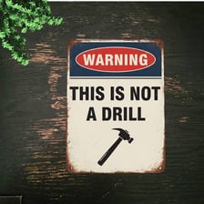 An emergency warning sign conveying that an alarm is not a drill.