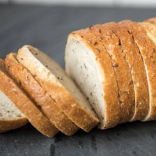 Several dark rye bread loaves with seeds on their crusts.