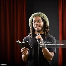 A poet reading a poem aloud at a microphone.