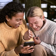 A person laughing while looking at a text message.