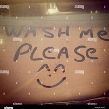 A dusty car with “Wash Me” written across its surface.