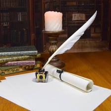 A calligraphy pen and ink beside lettering on paper