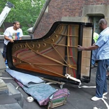Movers transporting a large grand piano.