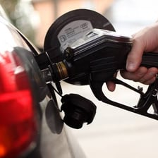 A gasoline pump nozzle filling a car