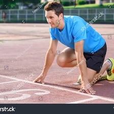 A runner crouches at a starting line before a race.