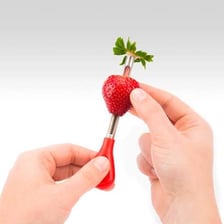 Green leafy strawberry tops separated from the red fruit.