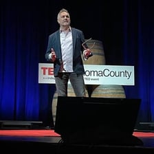 A speaker giving a presentation on a stage with a large red circle.