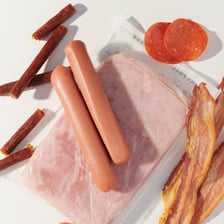 Assorted processed meats such as bacon, ham, and deli slices.