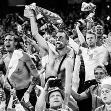 Fans cheer from the stands at a soccer match.
