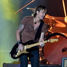 Keith Urban performing onstage with a guitar.