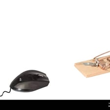 A traditional mouse trap placed next to a computer mouse pad