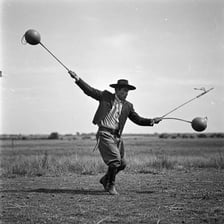 A gaucho holding a traditional bola made of weighted cords.