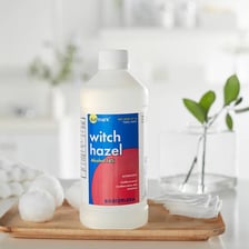 Witch hazel branches beside a bottle of witch hazel astringent