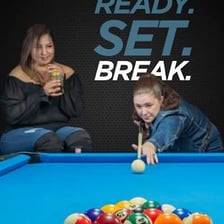 A billiards player striking the cue ball to begin a game.